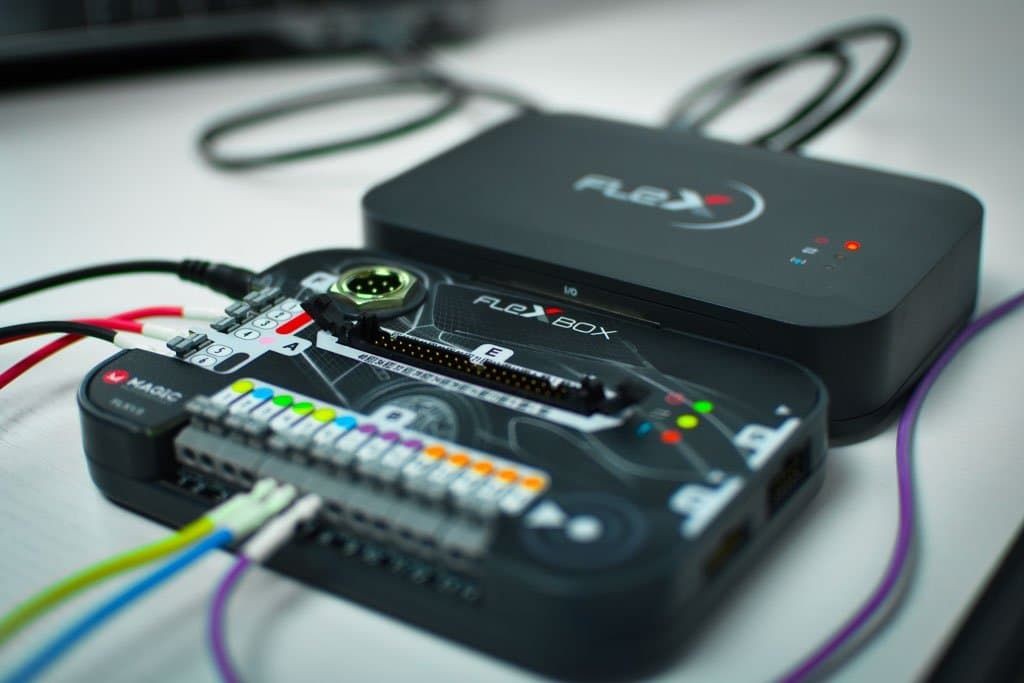 Close-up of electronic FlexBox device with multicolored wires connected on a desk.
