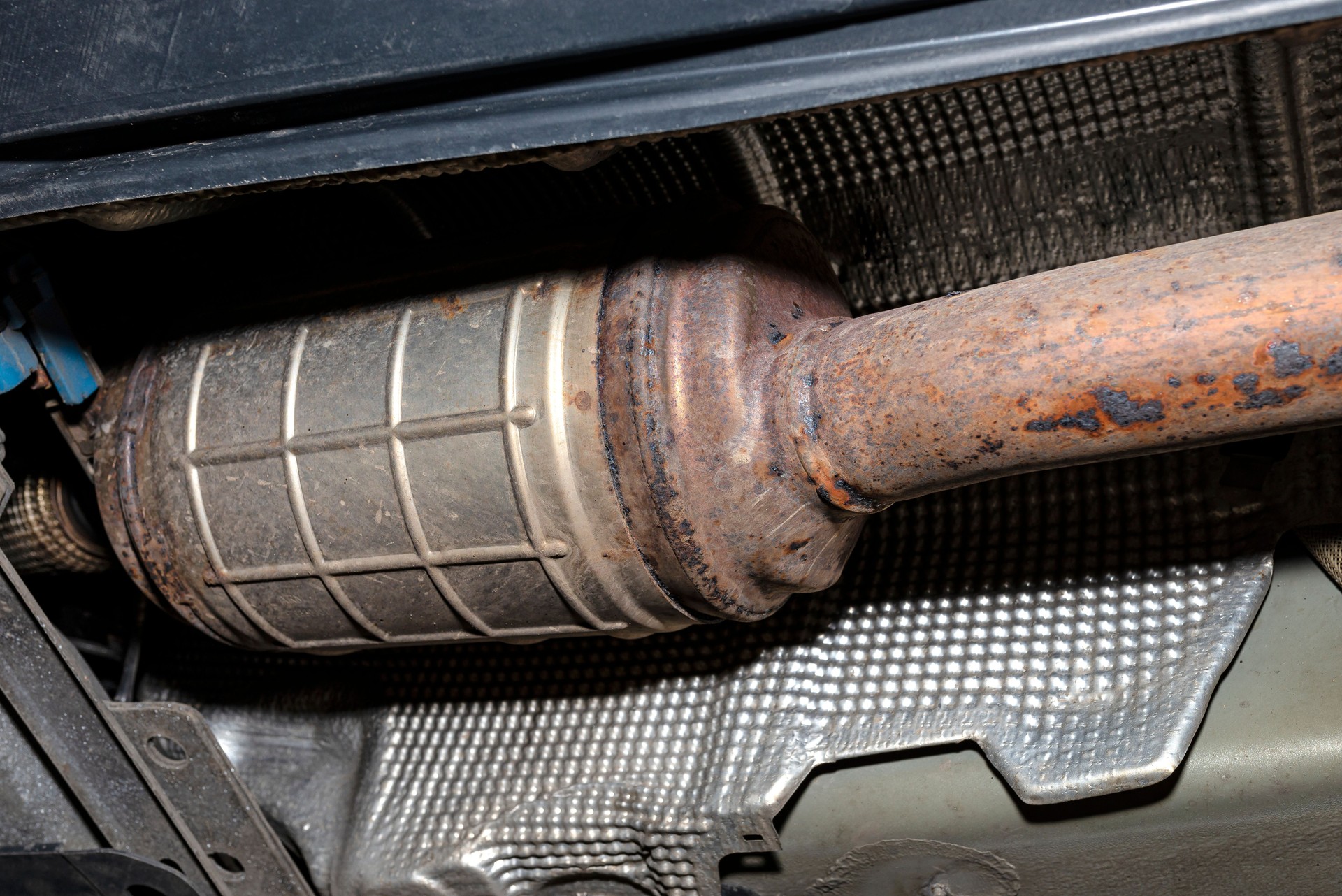 A diesel particulate filter in the exhaust system in a car on a lift in a car workshop, seen from below.